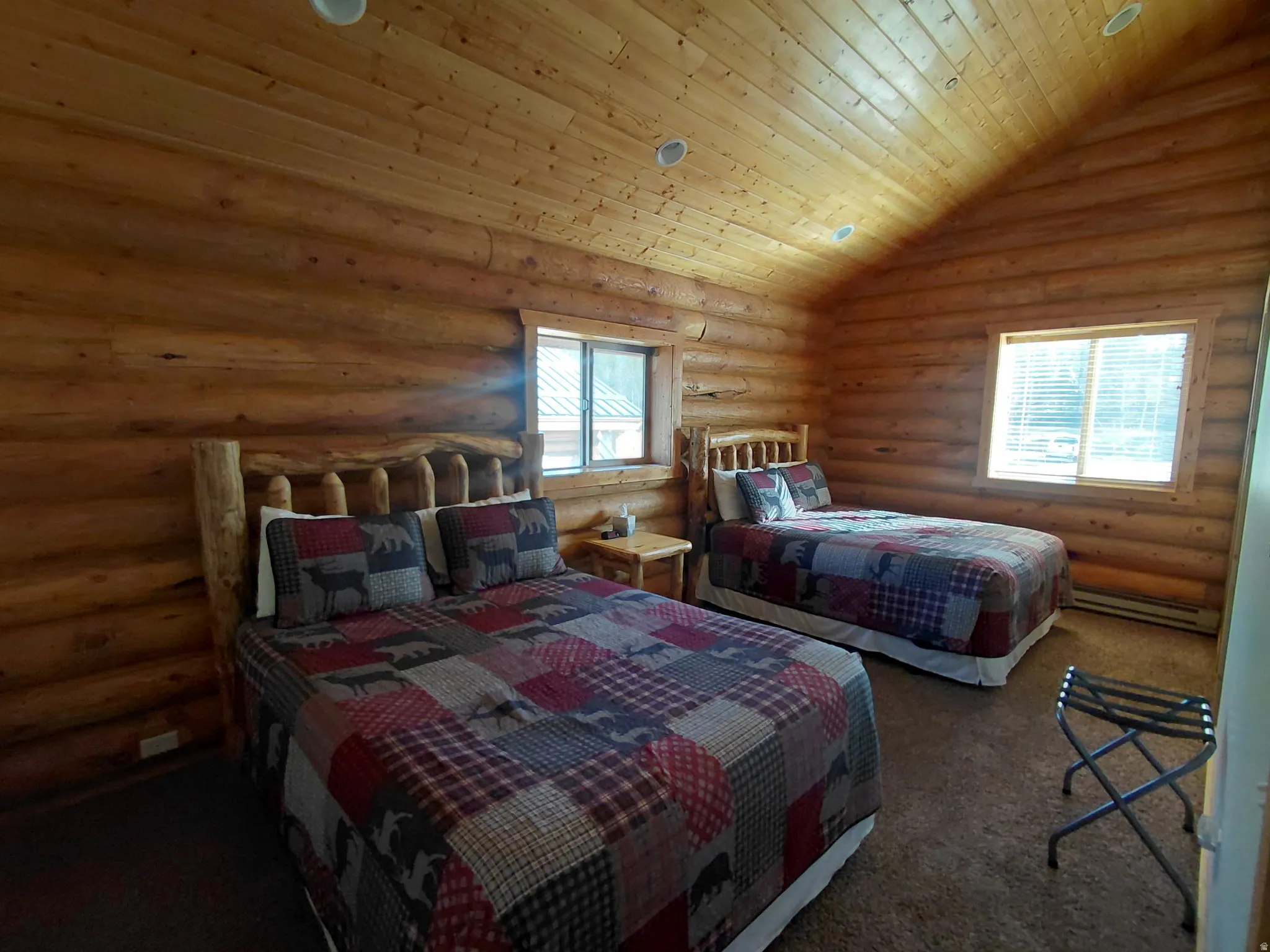 Room featuring natural log walls and a vaulted wood-paneled ceiling