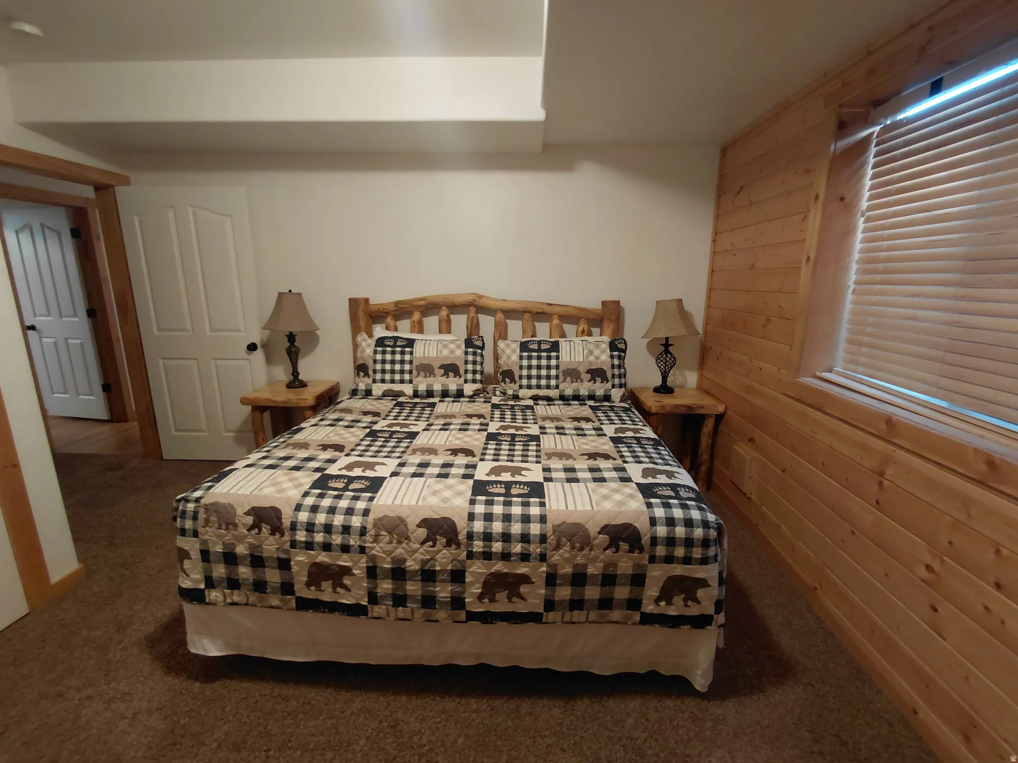 Bedroom featuring wood-paneled accent wall, brown carpet flooring, and a wood-finish door frame
