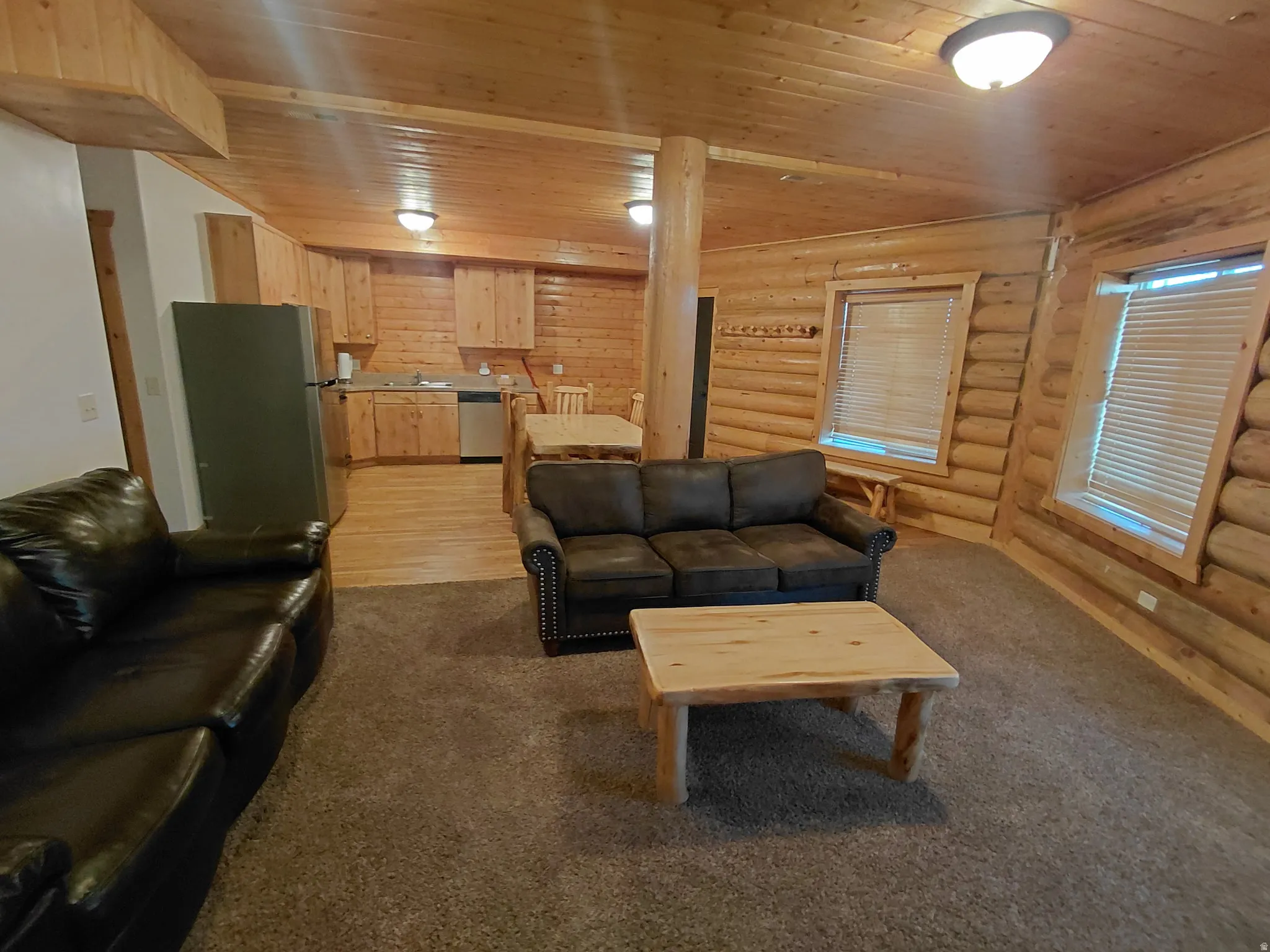 Open-concept living space featuring wood-finish walls and ceilings, recessed lighting, and a prominent wood structural column
