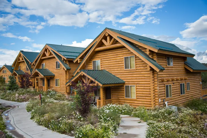 Row of log cabin-style residences featuring light wood construction and dark green metal roofing