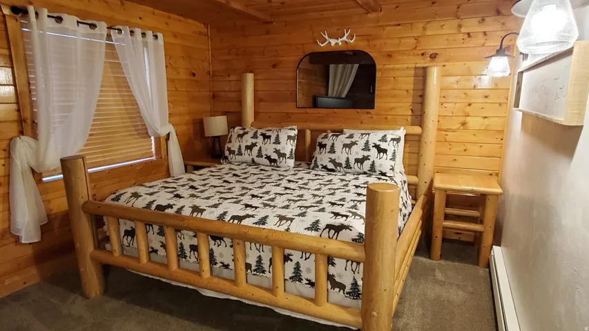 Wood-paneled room featuring a log-style bed frame, an arched wall niche, and built-in wall sconces