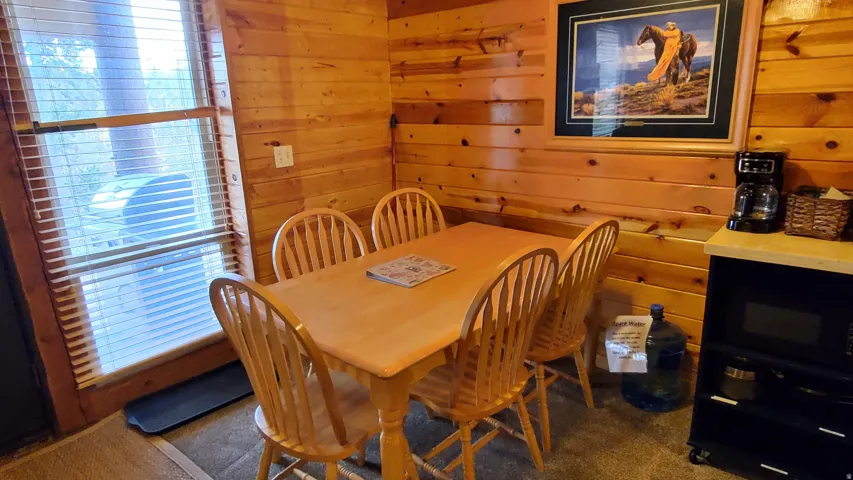 Dining area featuring wood-finish wall paneling and a large window with blinds