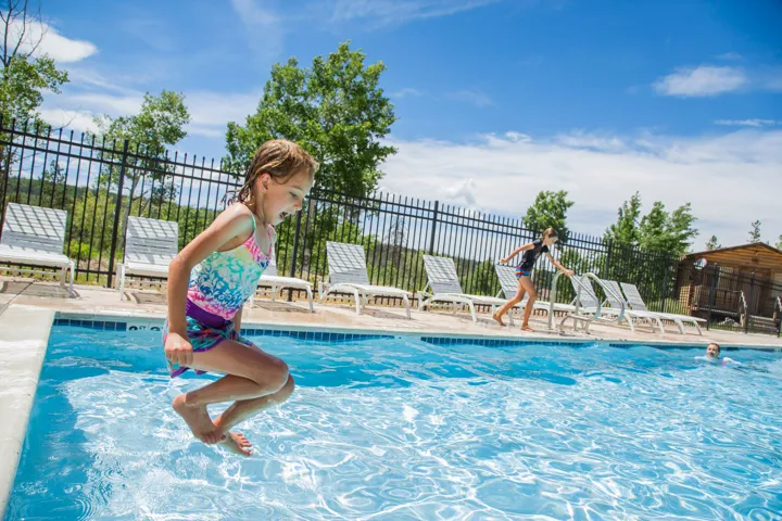 Outdoor swimming pool featuring a tiled edge, surrounding pool deck, and perimeter fencing