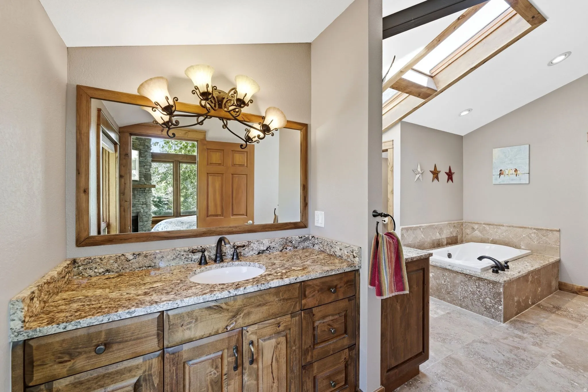 Bathroom featuring a rustic wood vanity with a granite countertop and undermount sink, bronze-finish faucet, and coordinating wood-framed mirror