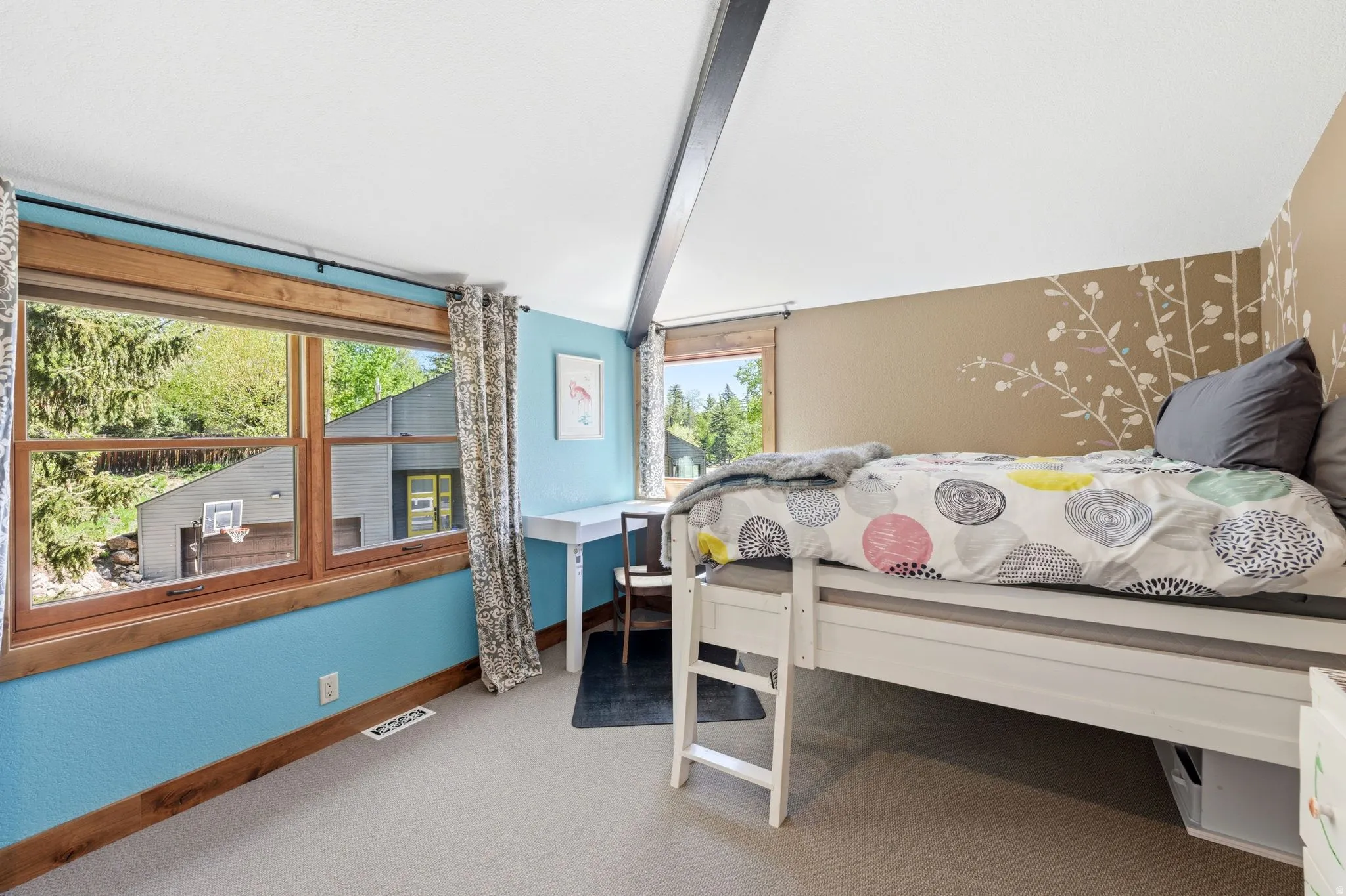 Sloped ceiling room featuring light-toned carpeting and wood-framed window