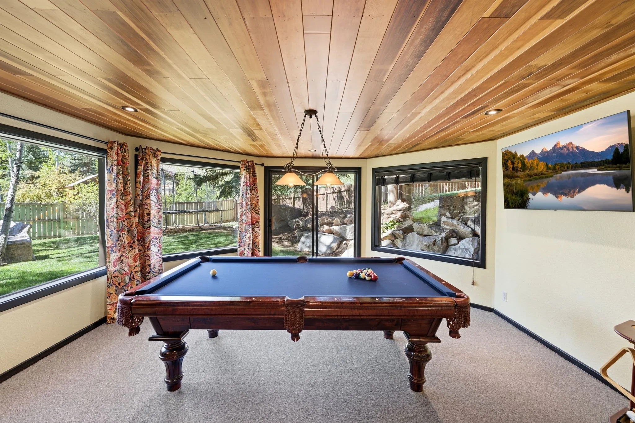 Room featuring a wood-panel ceiling with recessed lighting, multiple large windows, and neutral carpeting