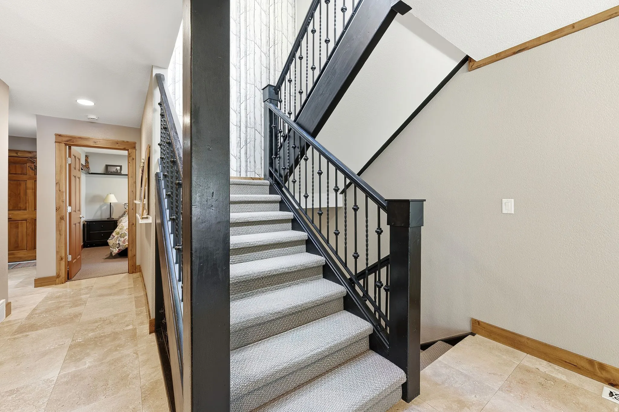 Carpeted staircase with wrought iron balusters and dark wood newel posts