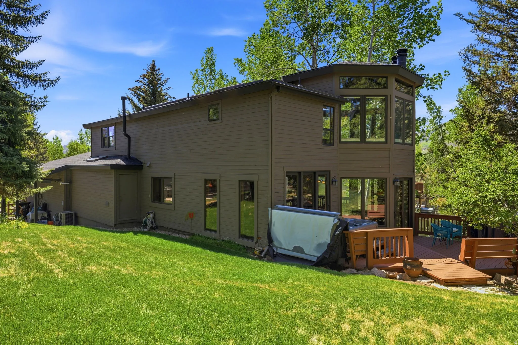 Spacious exterior with wood siding, a multi-level deck, and a prominent bay window