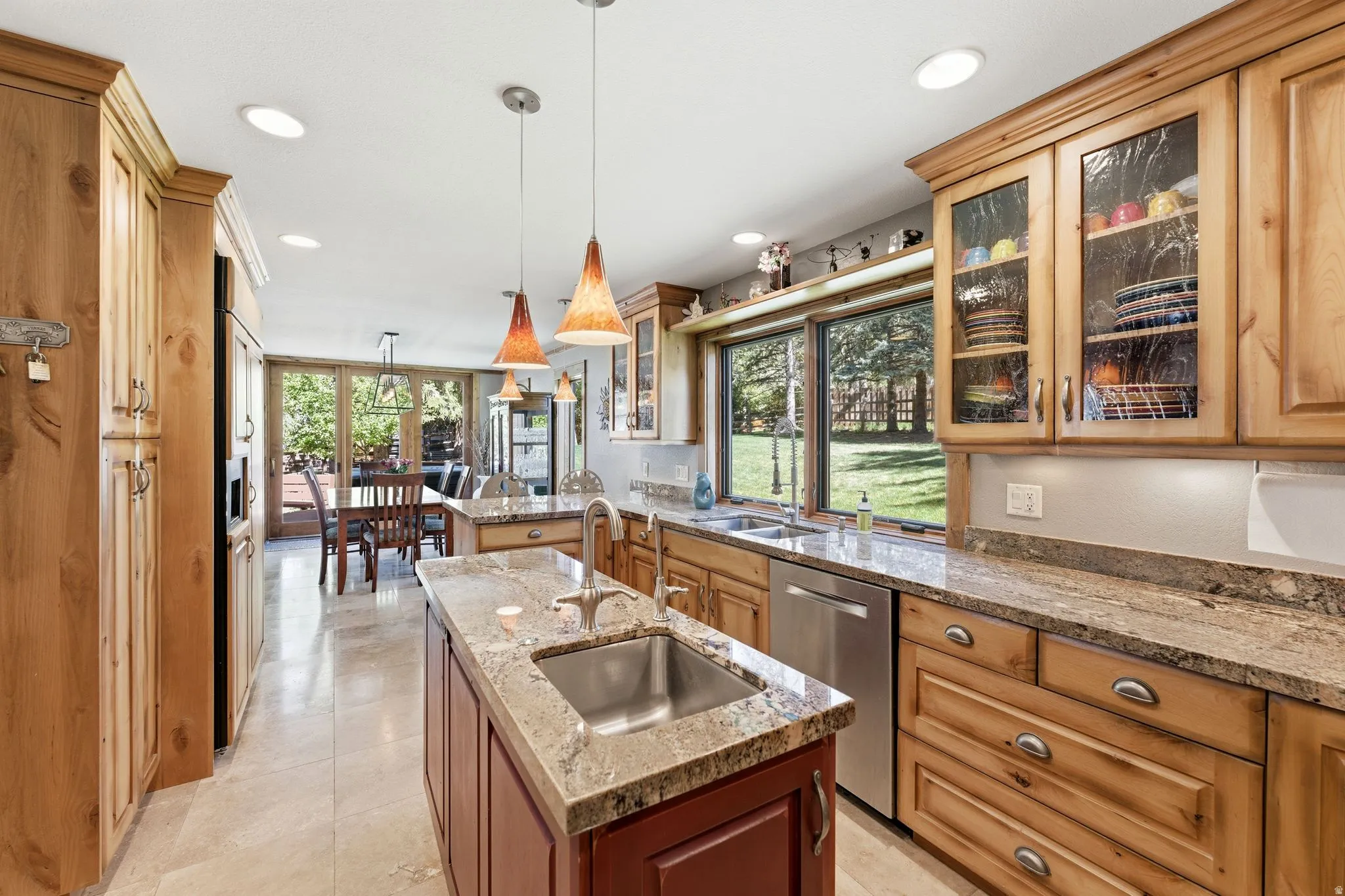 Bright kitchen featuring an island with a stainless steel sink, wood cabinetry, granite countertops, and recessed lighting