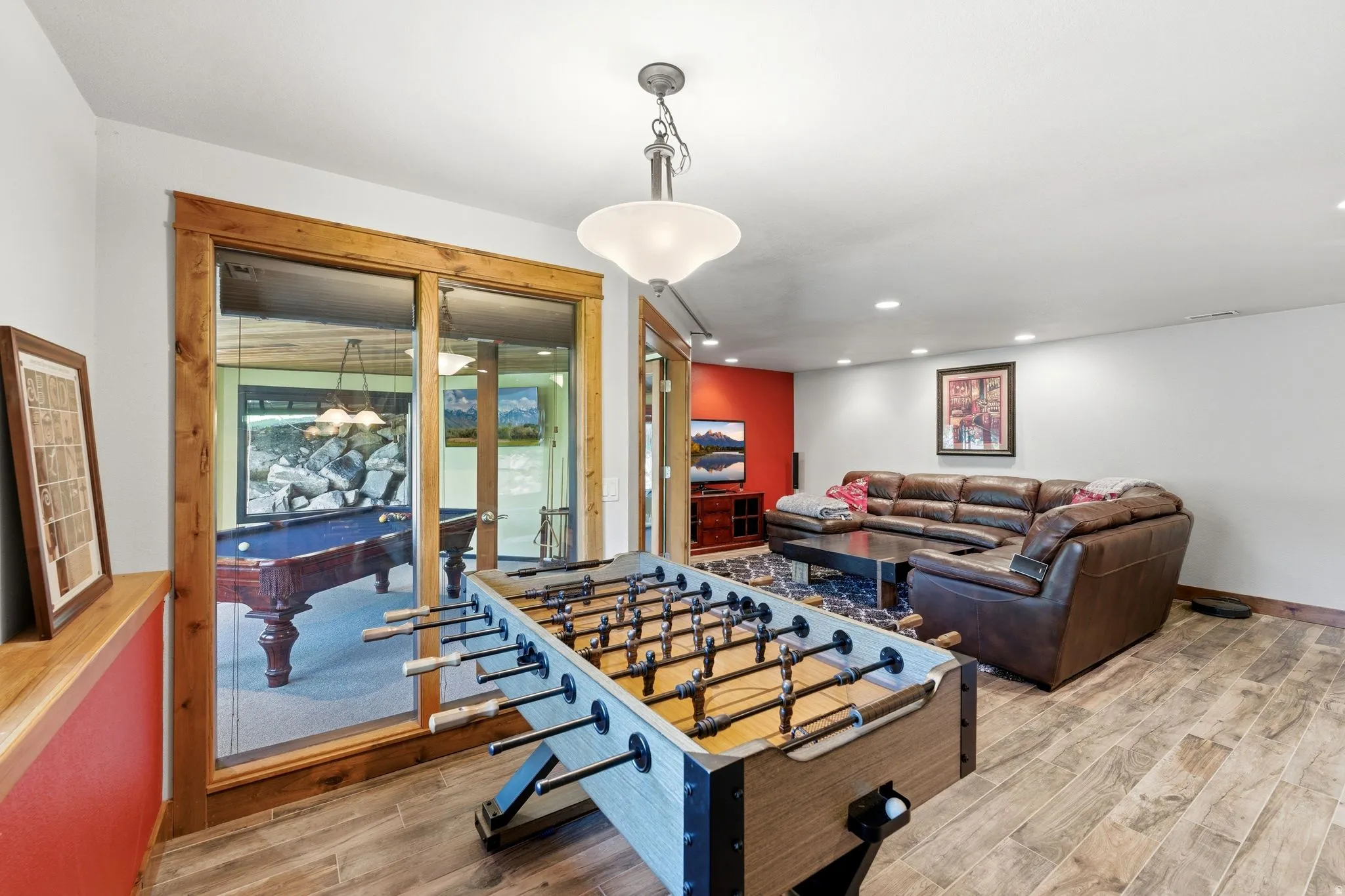 Spacious recreation room featuring wood-finish flooring, recessed lighting, and a prominent game table