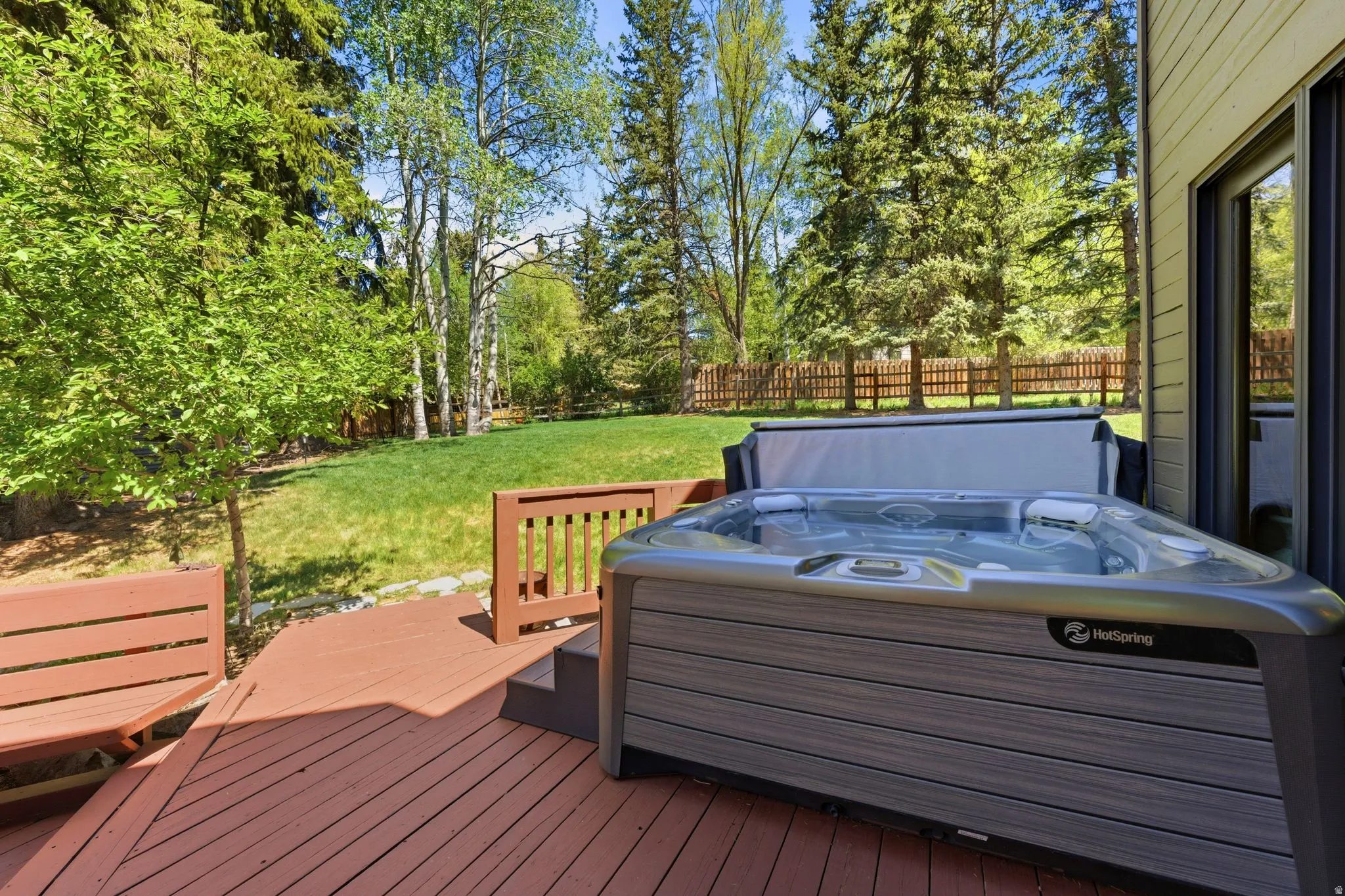 Expansive wood deck featuring a built-in bench and hot tub