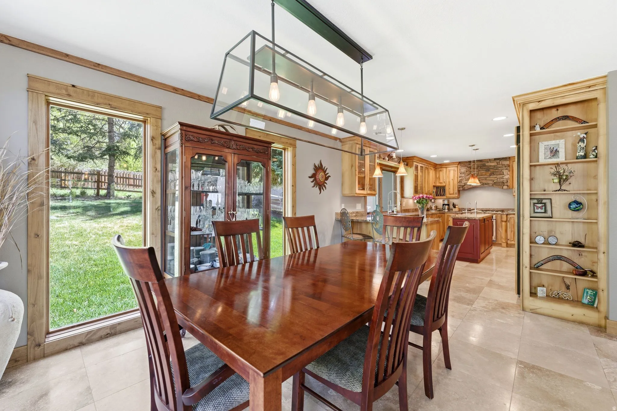Dining area featuring a modern linear chandelier, wood-finish flooring, and a built-in display cabinet