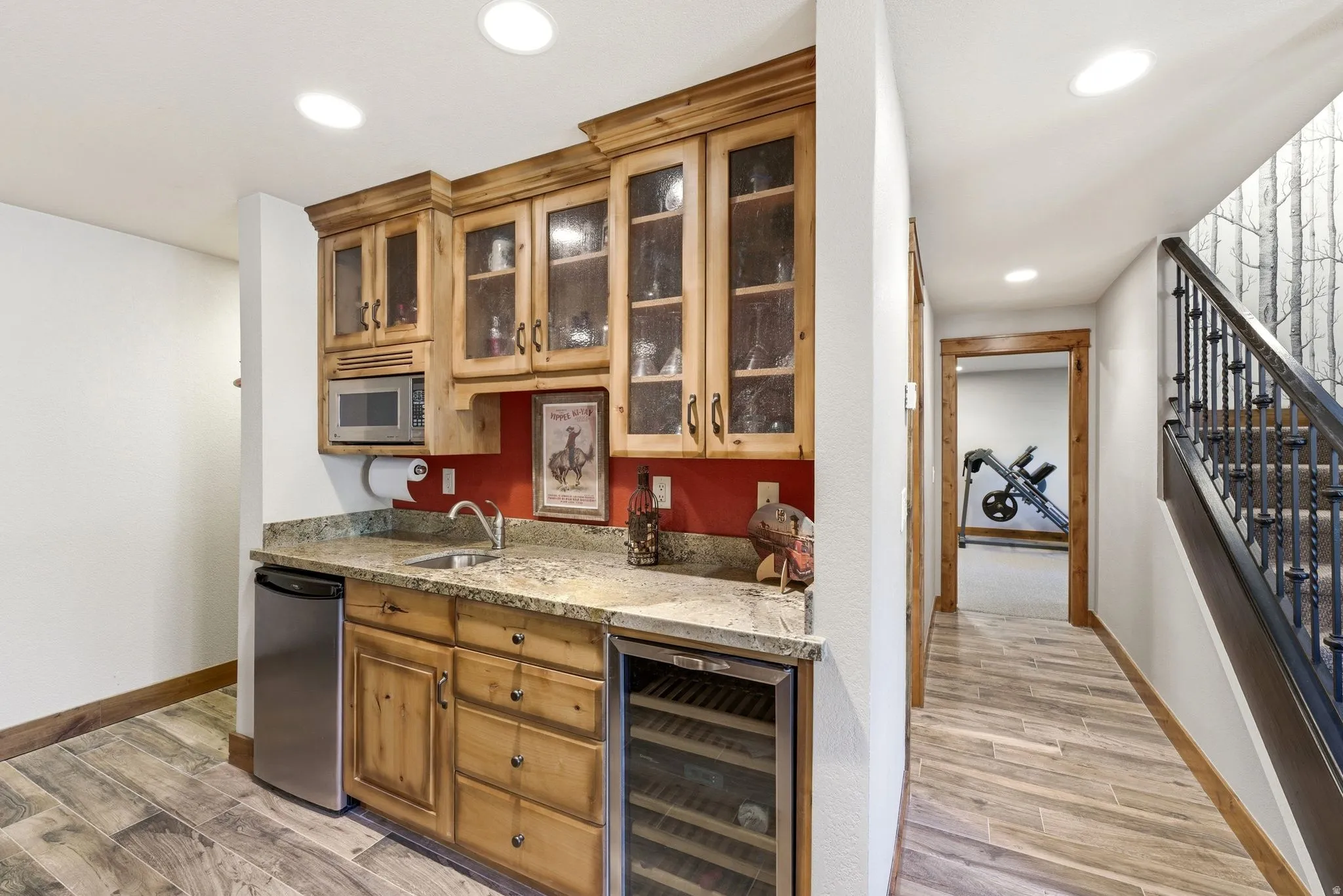 Wet bar featuring wood cabinetry, granite countertop, undermount sink, beverage cooler, and built-in microwave