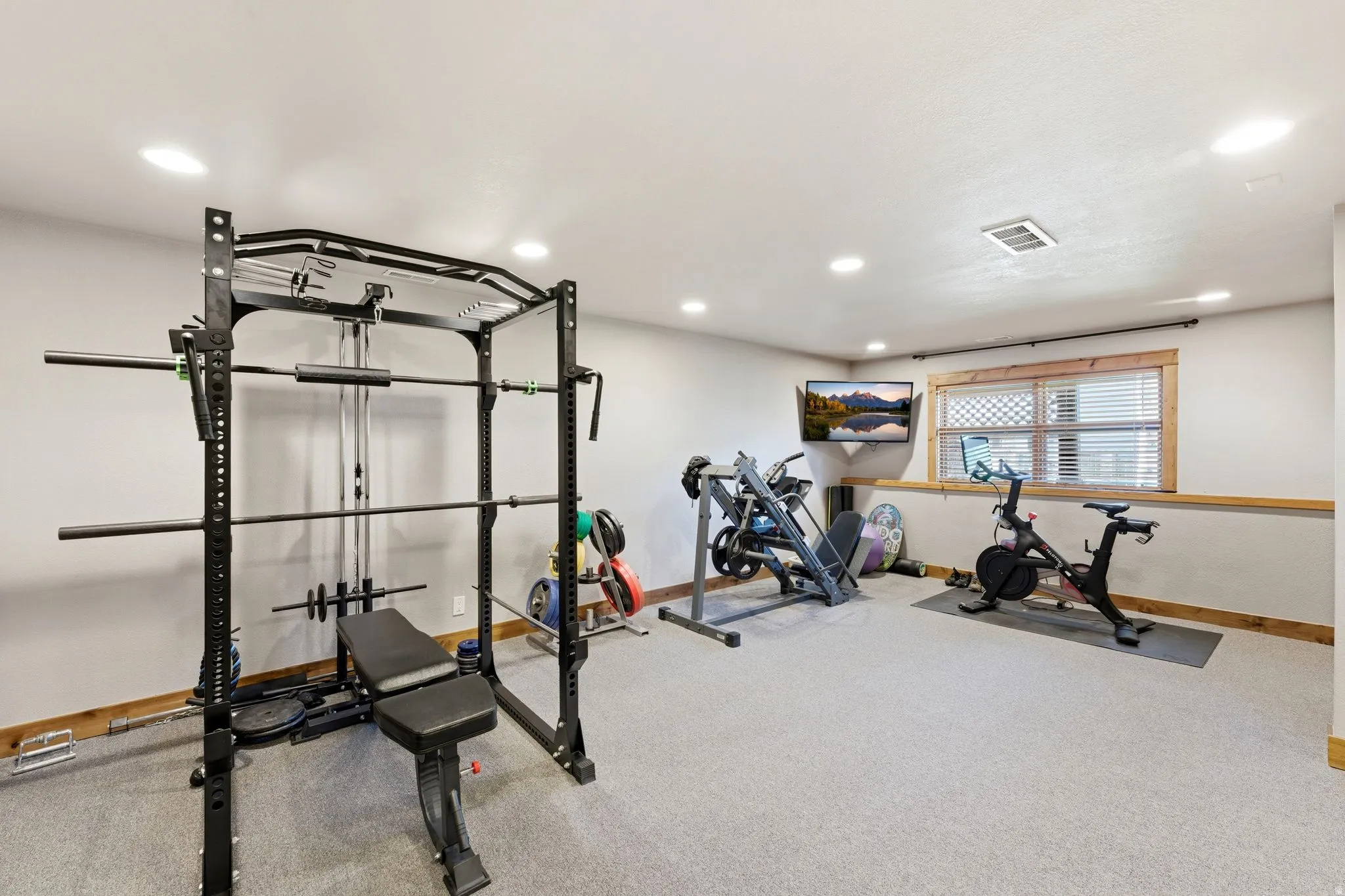 Versatile room featuring recessed lighting, light gray carpet, and a window with wood trim