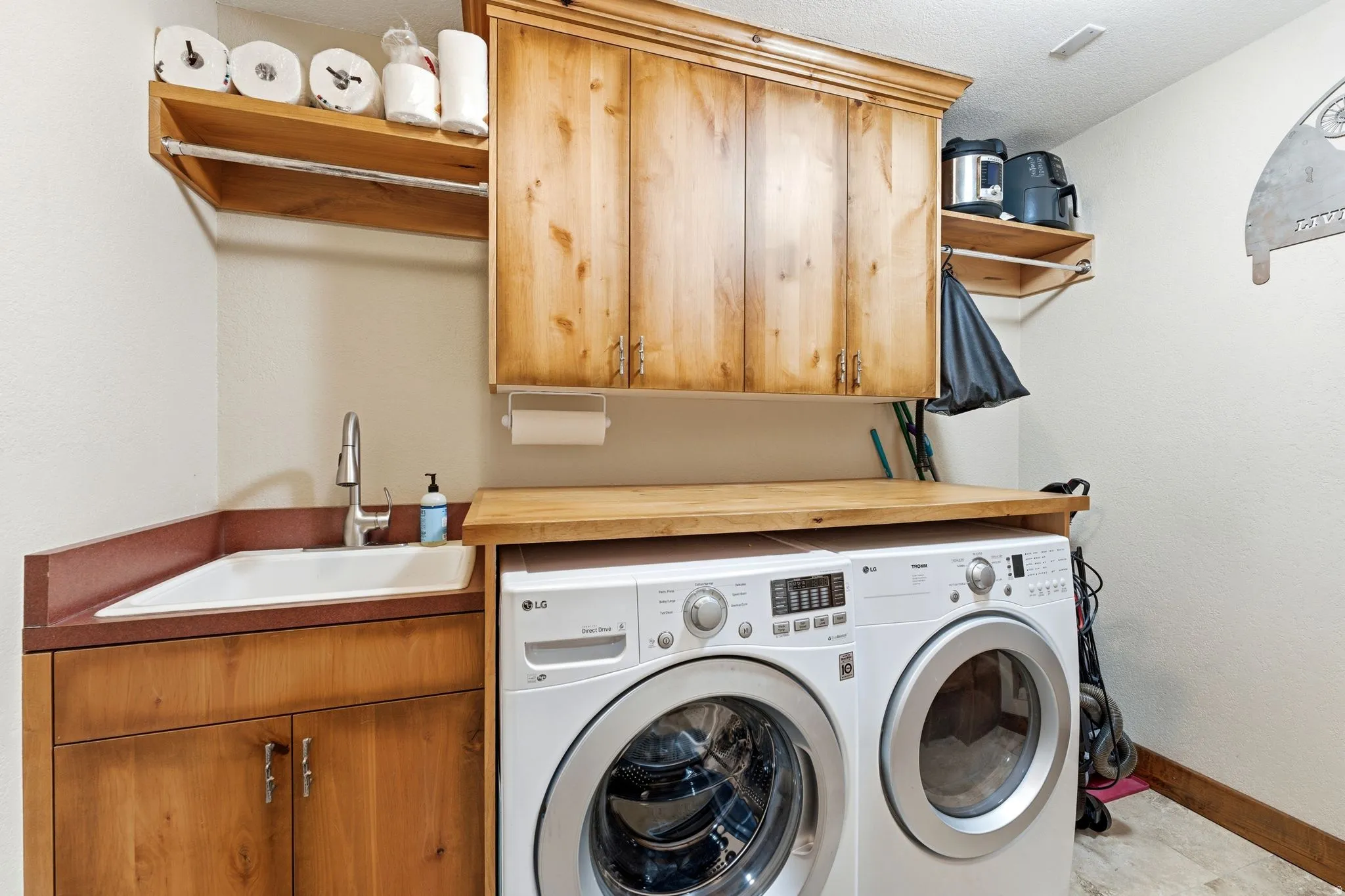 Functional utility space featuring a built-in sink with a gooseneck faucet, ample wood cabinetry, and an integrated wood-finish countertop
