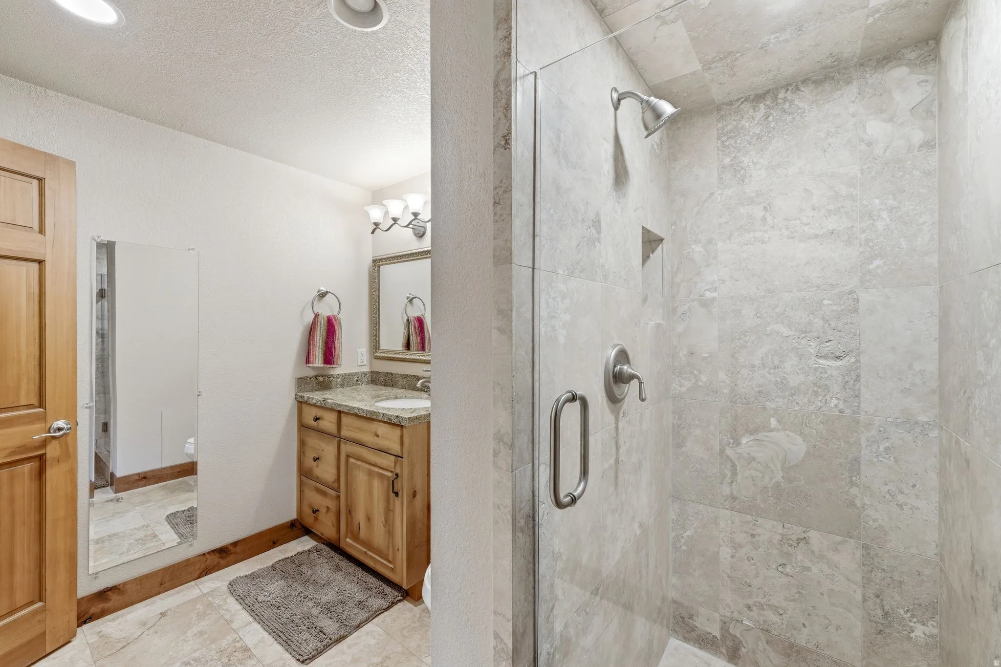 Glass-enclosed shower with large format tile surround, built-in niche, and brushed nickel fixtures
