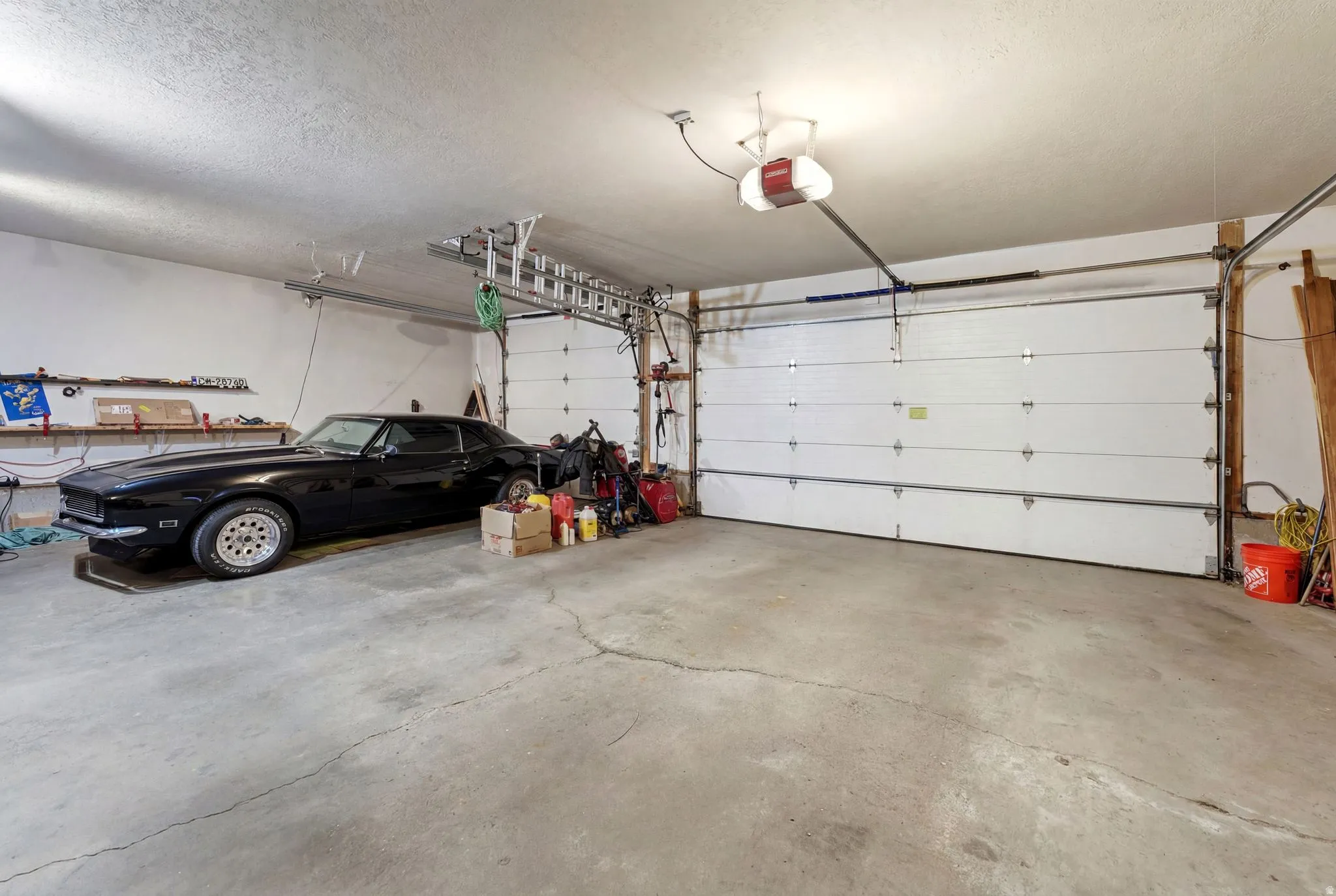 Attached two-car garage featuring a concrete floor, white panel garage door, and ample overhead lighting