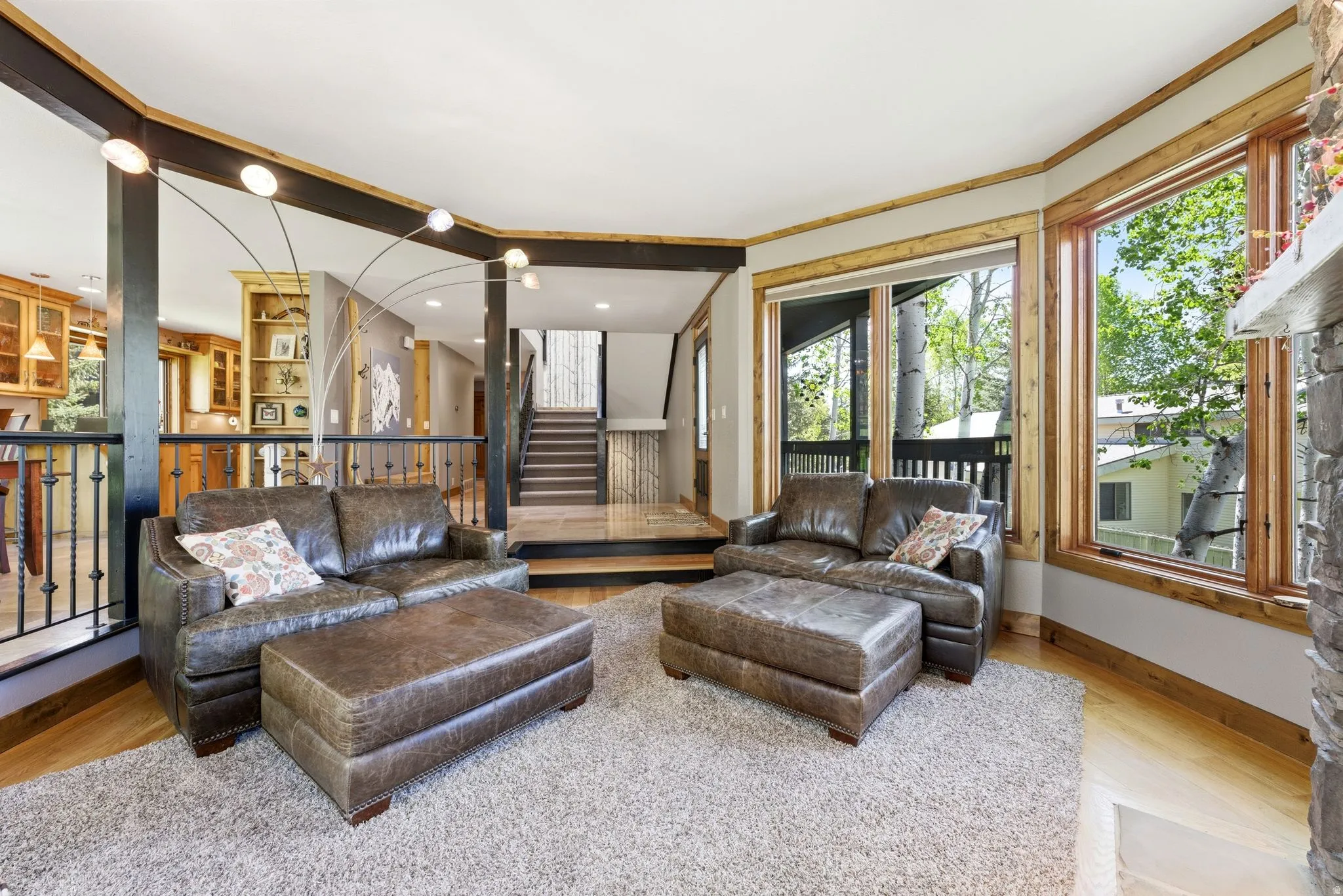 Living space featuring large windows, wood-finish flooring, and a stone fireplace