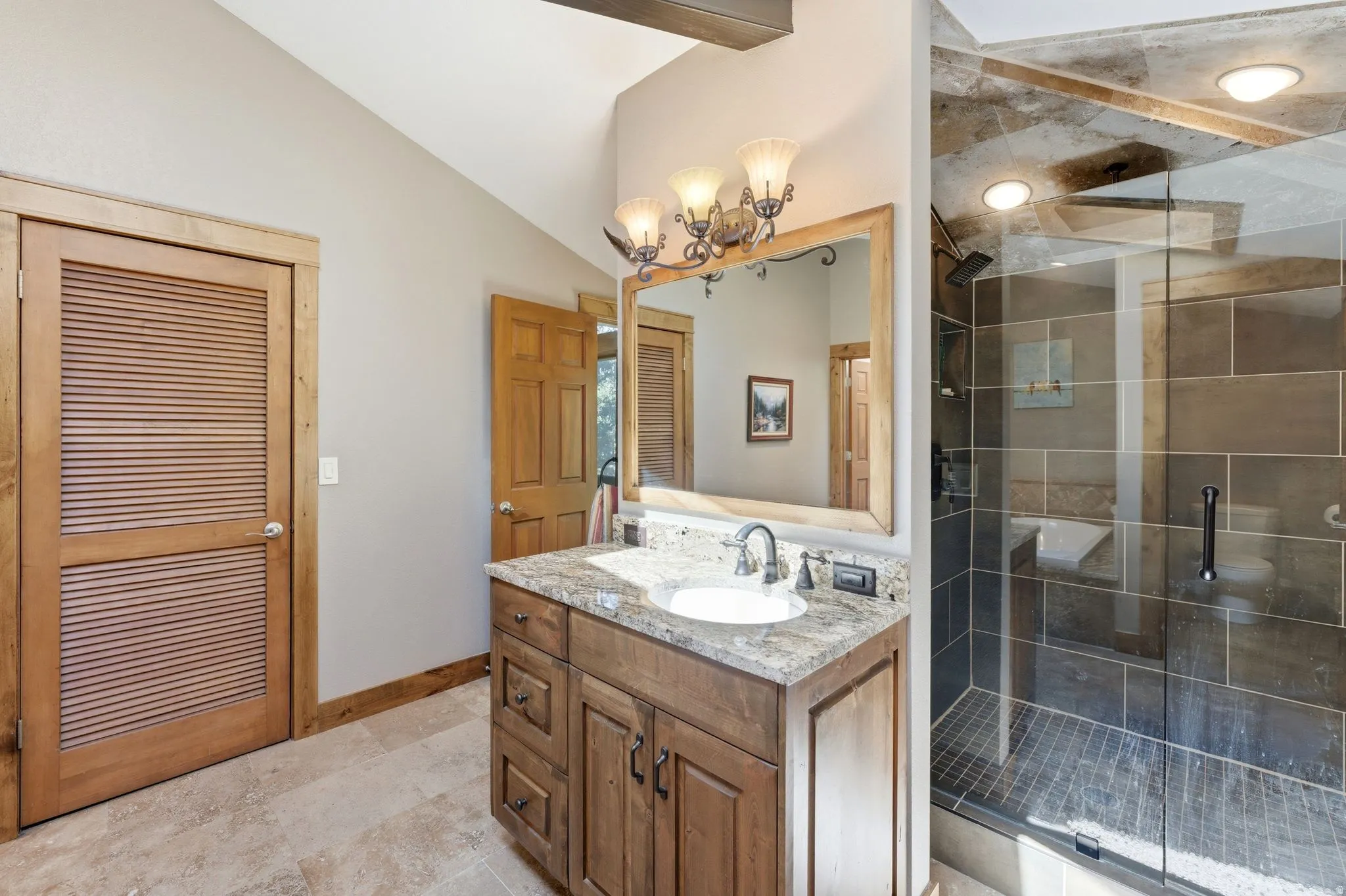 Bathroom featuring a single vanity with stone countertop, undermount sink, and wood-finish cabinetry