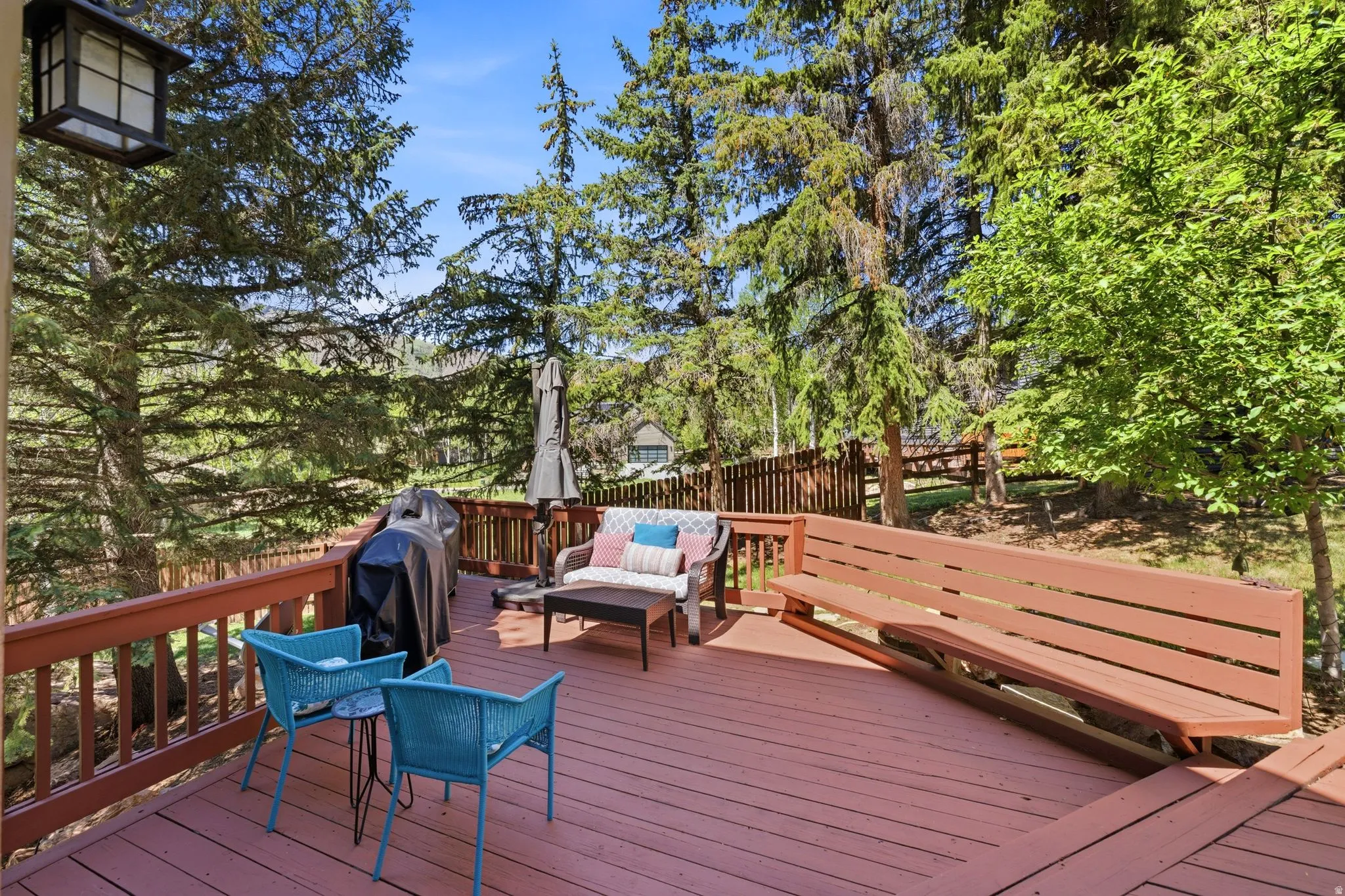 Multi-level wood deck featuring a built-in bench, wood railing, and mature surrounding trees