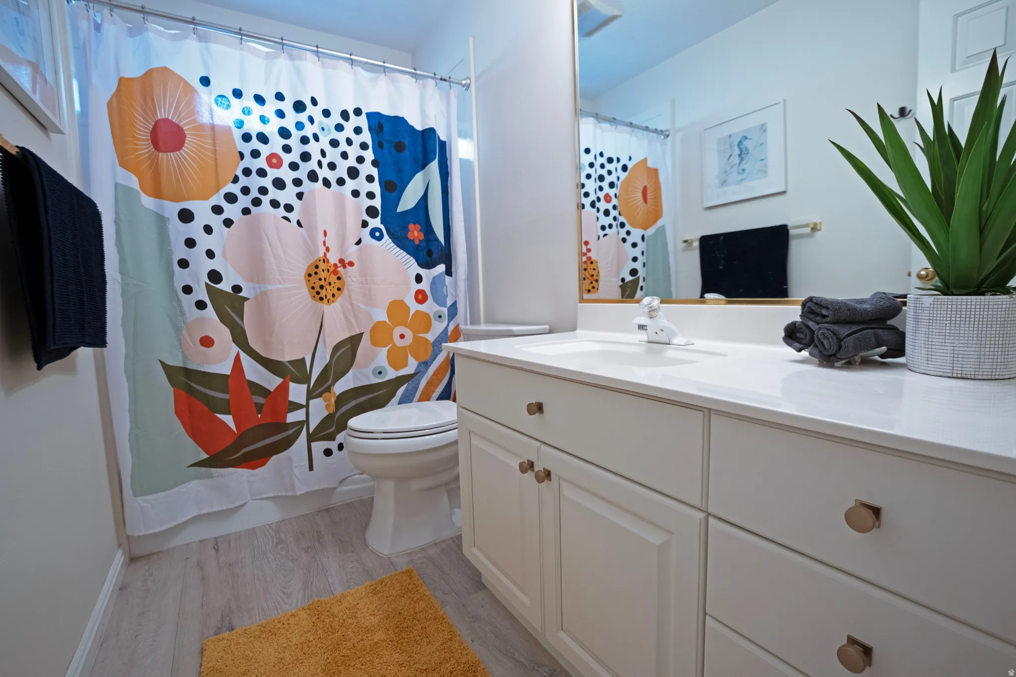 Bathroom vanity featuring a white countertop, an integrated sink, and white cabinetry with round brass hardware