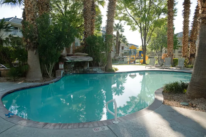Resort-style swimming pool featuring a curved design and integrated waterfall