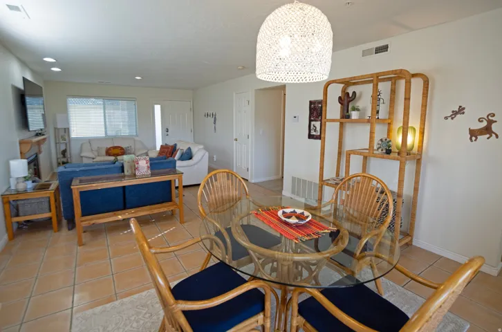 Open concept living and dining area featuring tile flooring, a glass-top dining table, and a decorative shelving unit