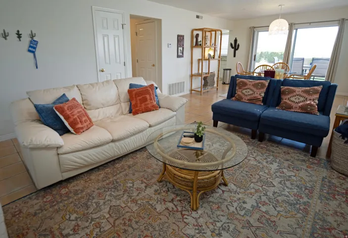 Open concept living area featuring light-toned walls, tile flooring, and direct access to an outdoor patio via sliding glass doors