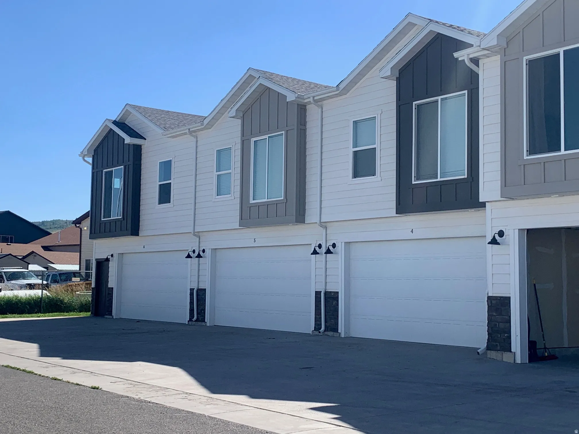 Contemporary townhome facades featuring horizontal siding in white and vertical paneling in charcoal and grey tones