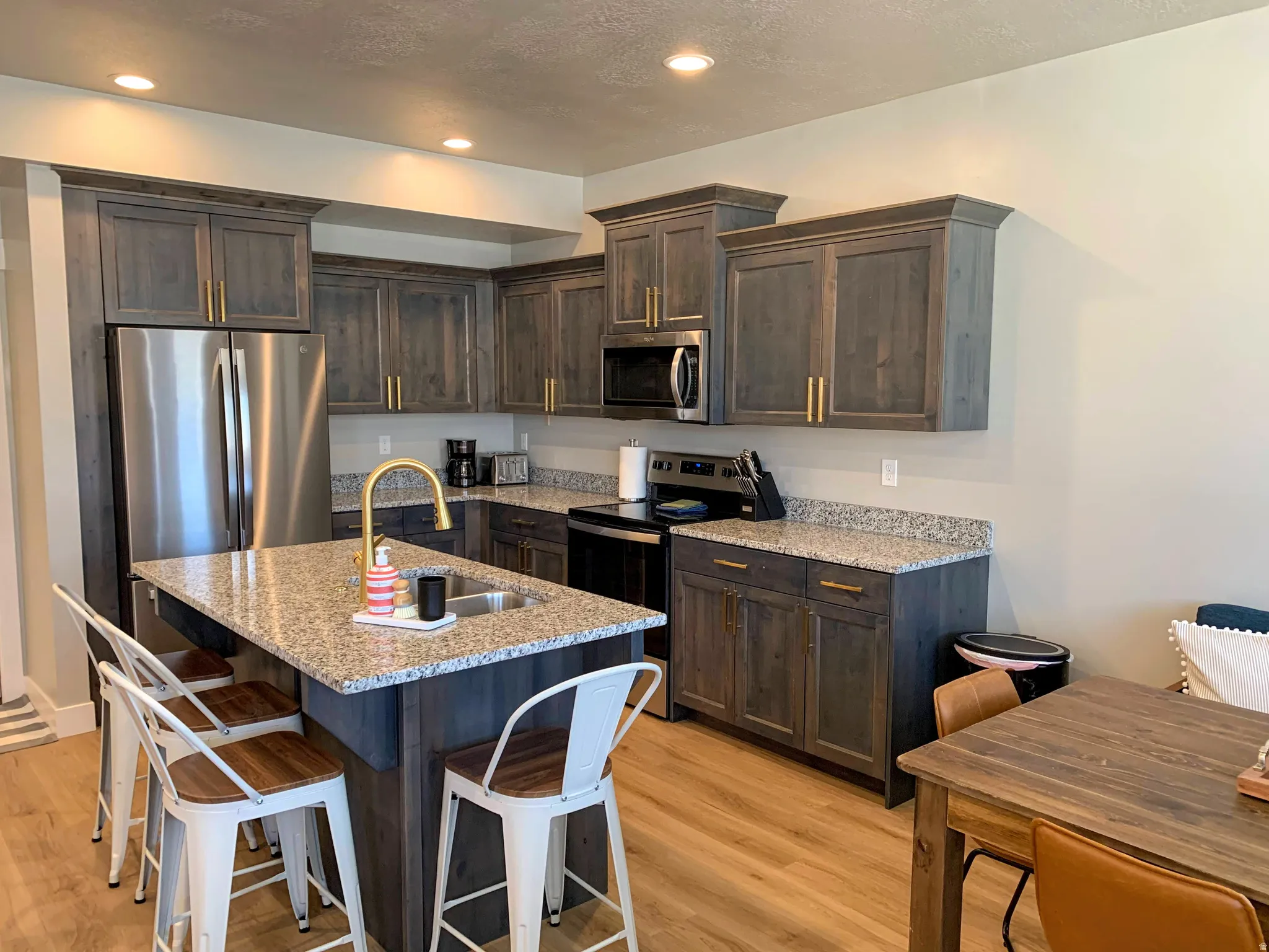 Kitchen featuring wood-finish flooring, recessed lighting, and dark wood cabinetry with gold hardware