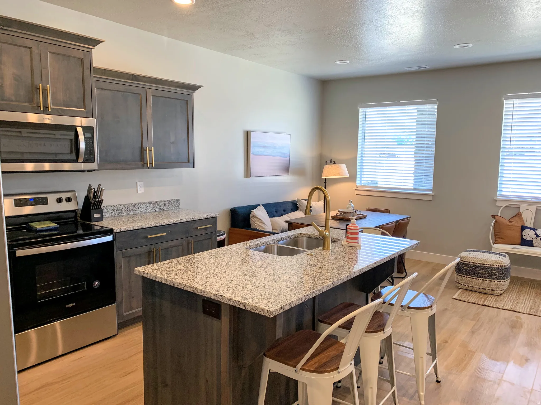 Kitchen and dining area featuring a central island with dual sinks and bar seating