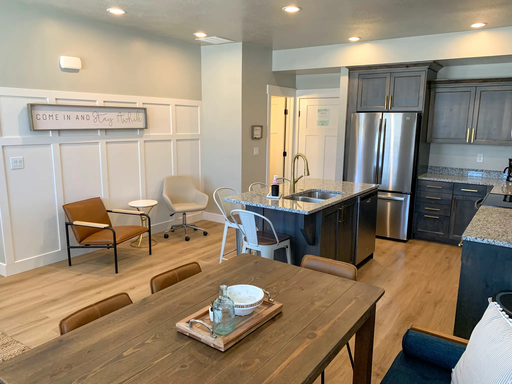 Open-concept living space with light wood-finish flooring, recessed lighting, and white wainscoting