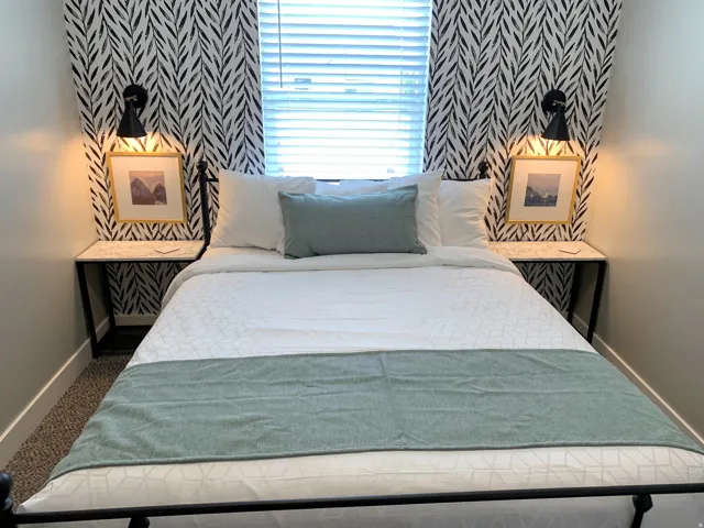 Bedroom featuring a decorative accent wall, built-in sconce lighting, and a window with blinds