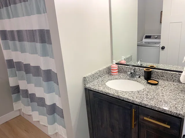 Modern bathroom vanity featuring a granite countertop with an undermount sink and dark wood-finish cabinetry