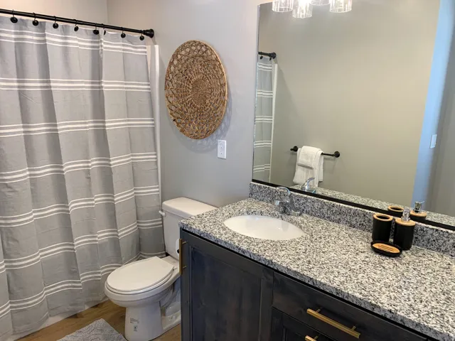 Bathroom featuring a spacious vanity with a granite countertop, undermount sink, and dark wood-finish cabinetry with brass hardware