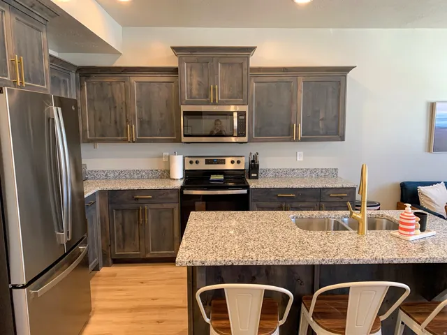 Kitchen featuring distressed wood-finish cabinetry with gold-tone hardware, a stainless steel refrigerator, and a built-in microwave