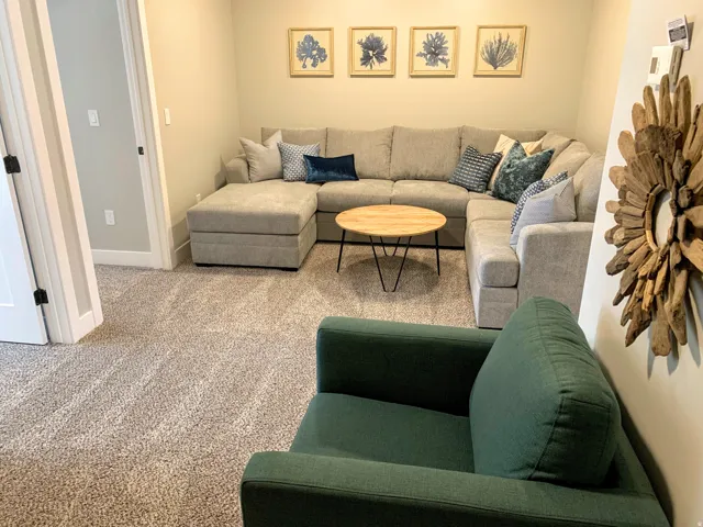 Carpeted interior space featuring light-colored walls and a corner seating area