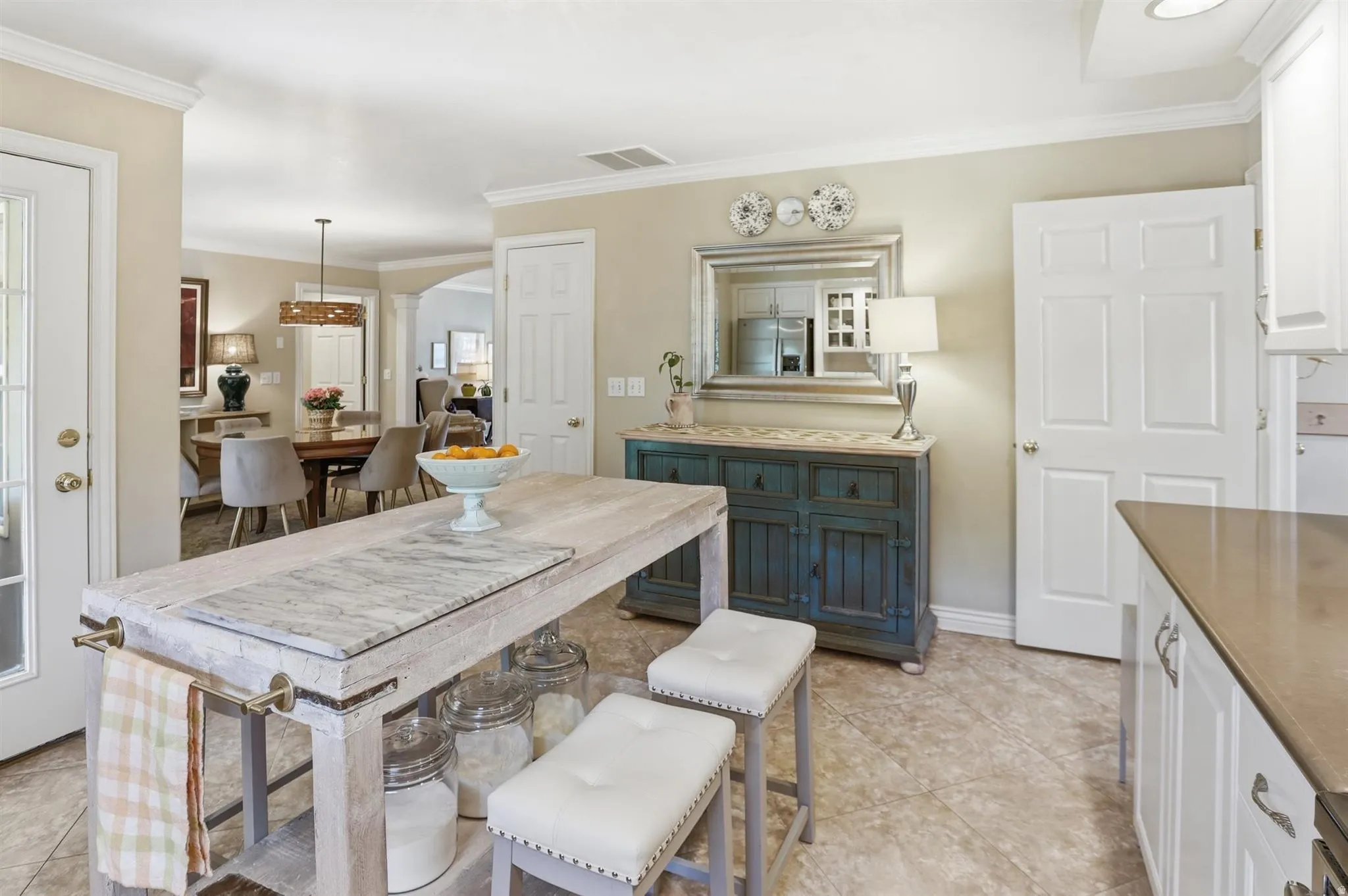 Kitchen featuring a wood-finish island with integrated towel bars and a stone-finish countertop insert, tile flooring, and perimeter cabinetry with a solid surface countertop