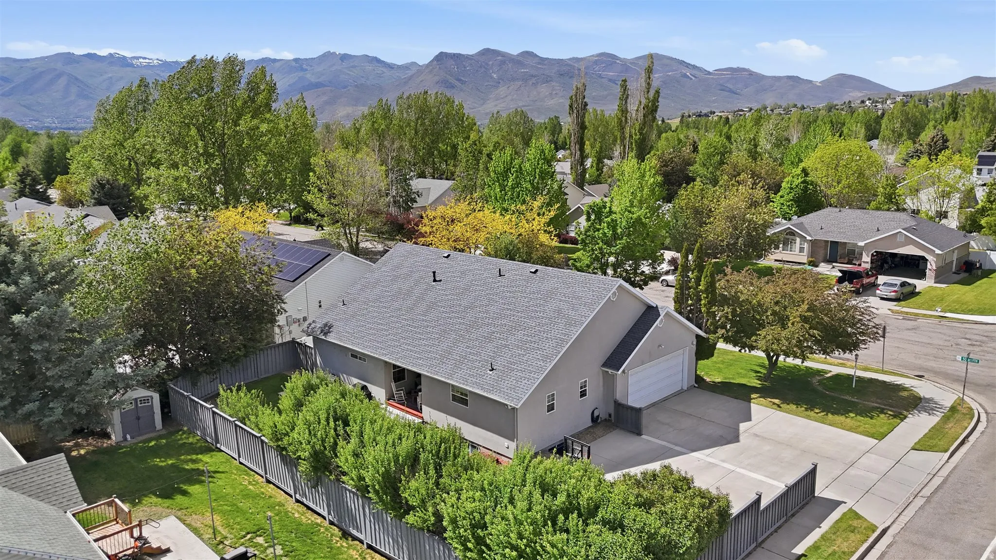 Rambler residence featuring a gray shingle roof, attached two-car garage, and a fenced backyard with green lawn