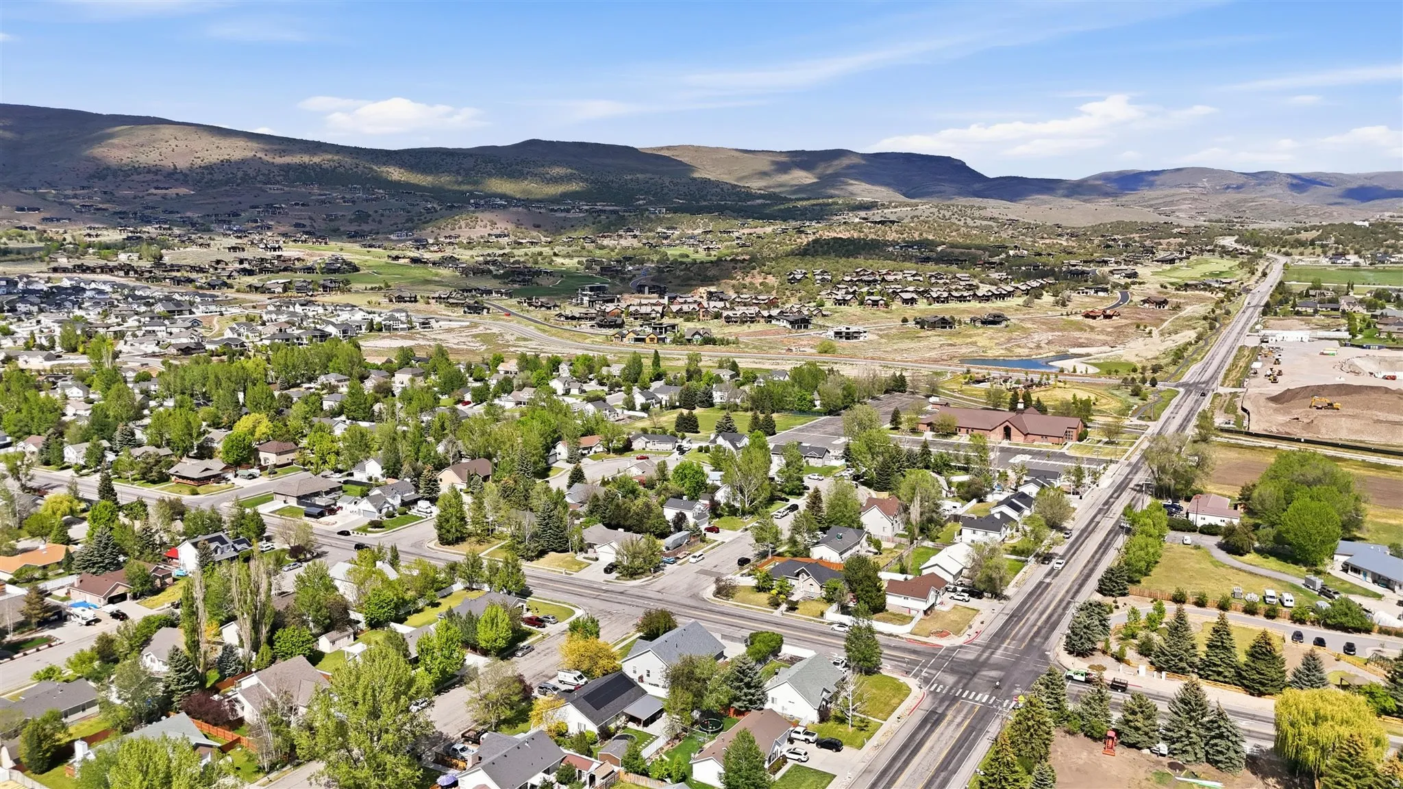 Aerial perspective showcasing a residential community with mature trees and paved roads, set against a backdrop of distant mountains