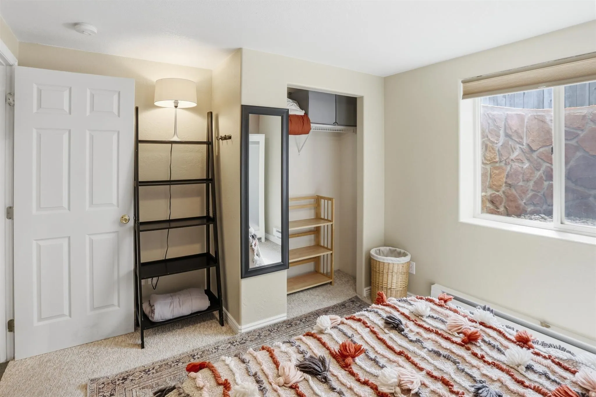 Bedroom 4 space featuring a window with stone-look exterior, open closet with built-in shelving, and light-colored wall paint