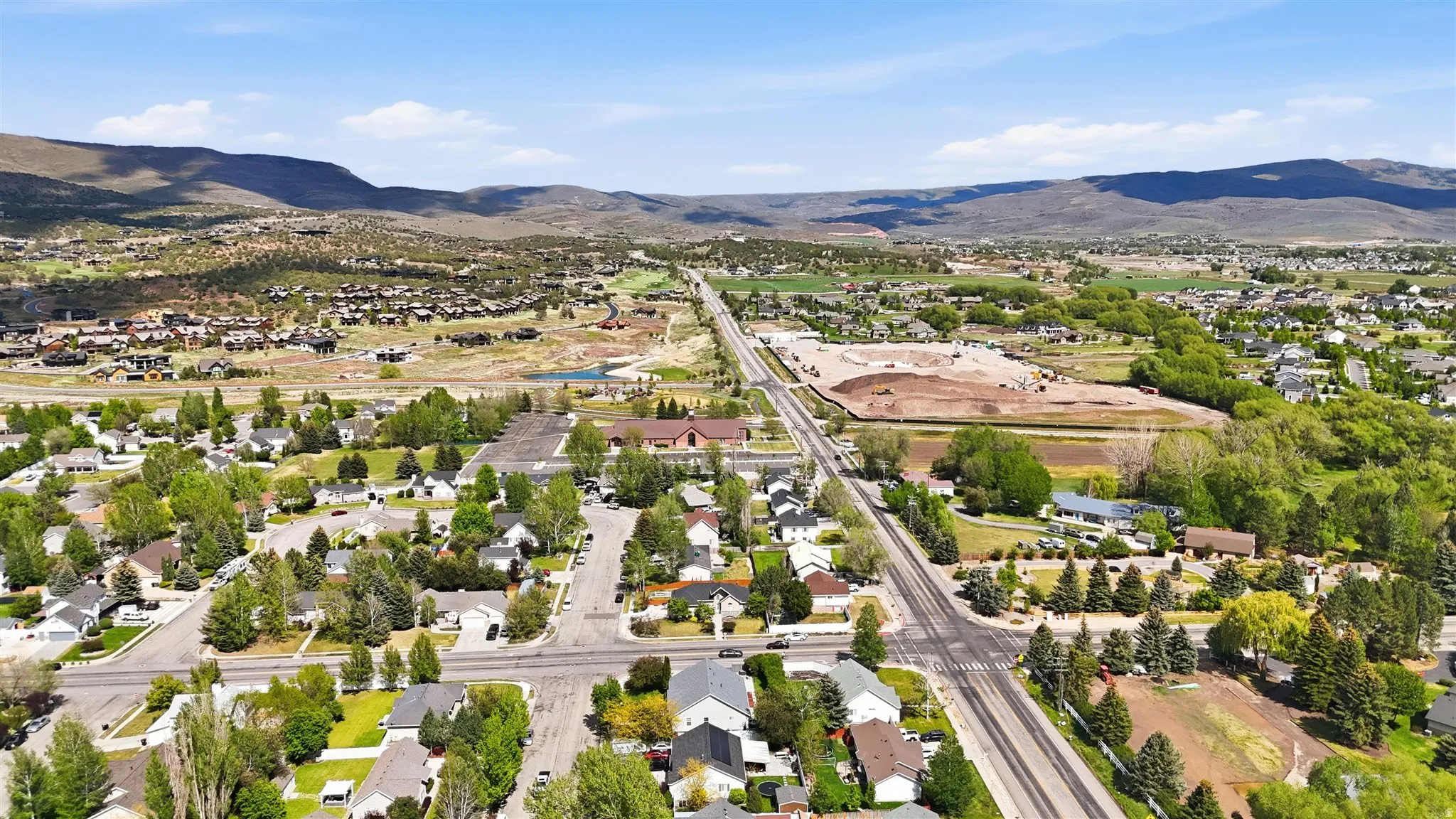 Aerial perspective showcasing a residential area with varied housing styles, mature trees, and paved streets