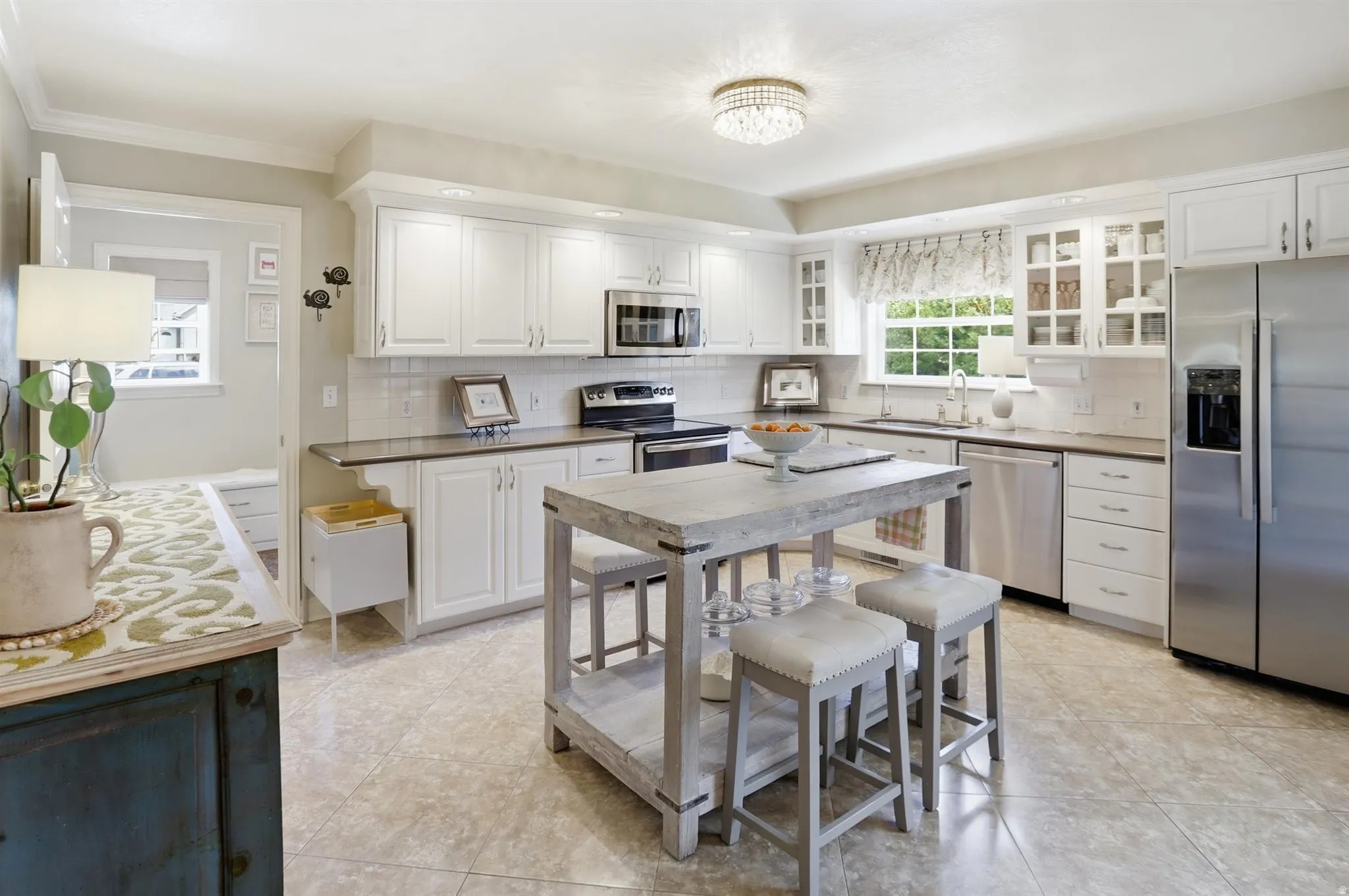 Kitchen featuring an island with seating, white shaker-style cabinetry, stainless steel appliances, and a tile backsplash