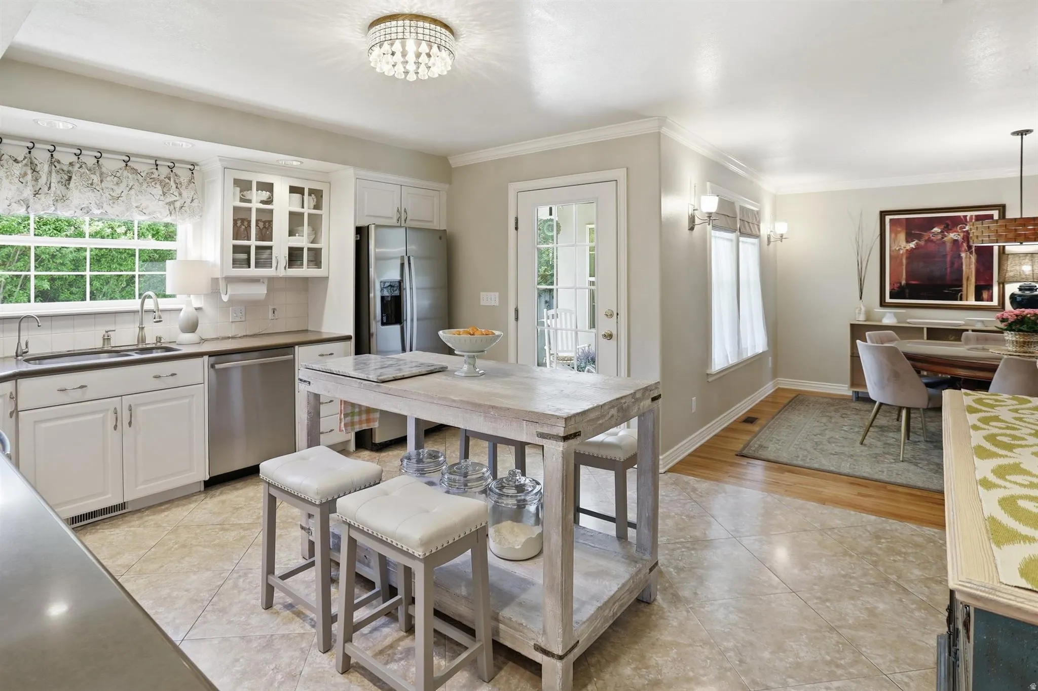 Kitchen featuring white cabinetry, stainless steel appliances, a center island with seating, a tile backsplash, and a glass-paneled exterior door