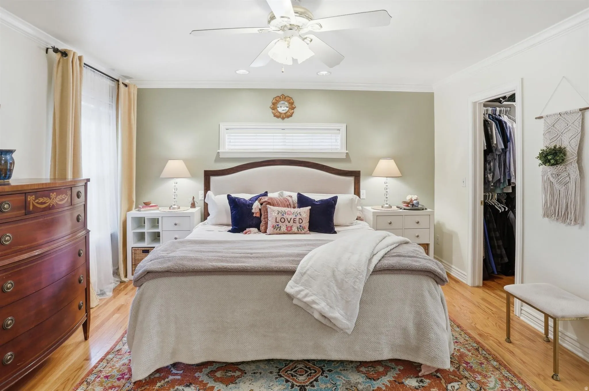 Bedroom featuring wood-finish flooring, a ceiling fan with integrated lighting, and a closet with built-in shelving and hanging rods