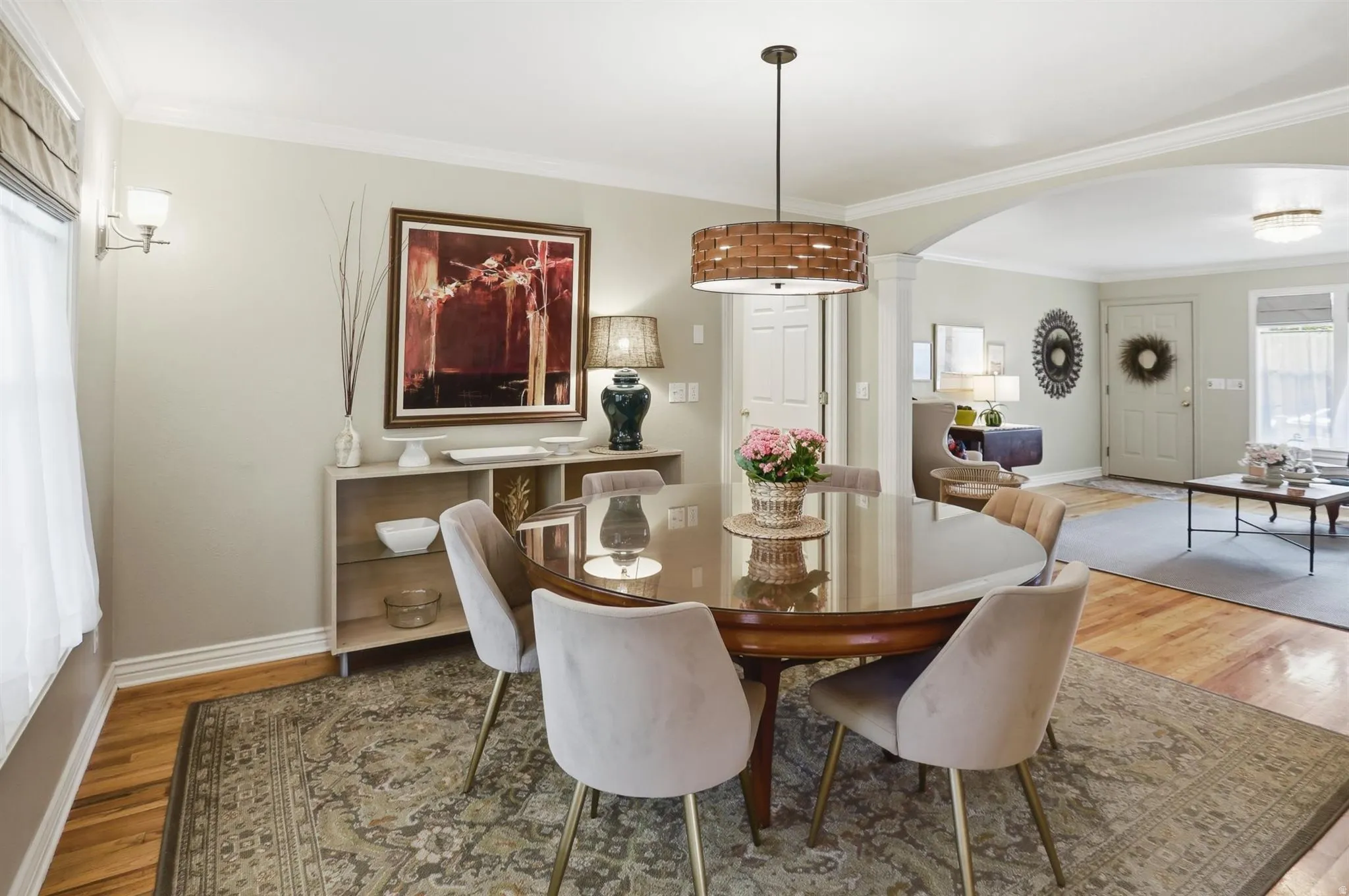 Dining area featuring wood-finish flooring, a contemporary drum pendant light, and an arched doorway leading to an additional living space