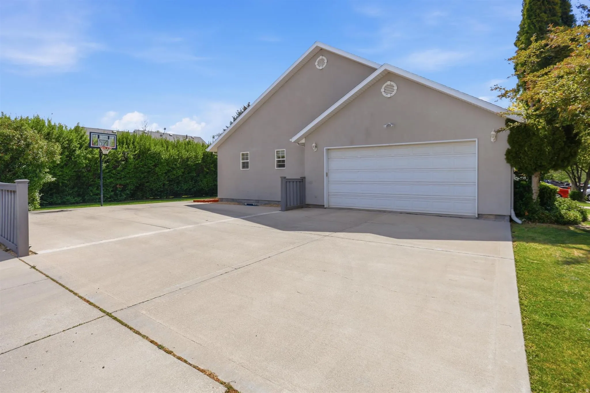 Expansive concrete driveway and recreational court featuring a basketball hoop