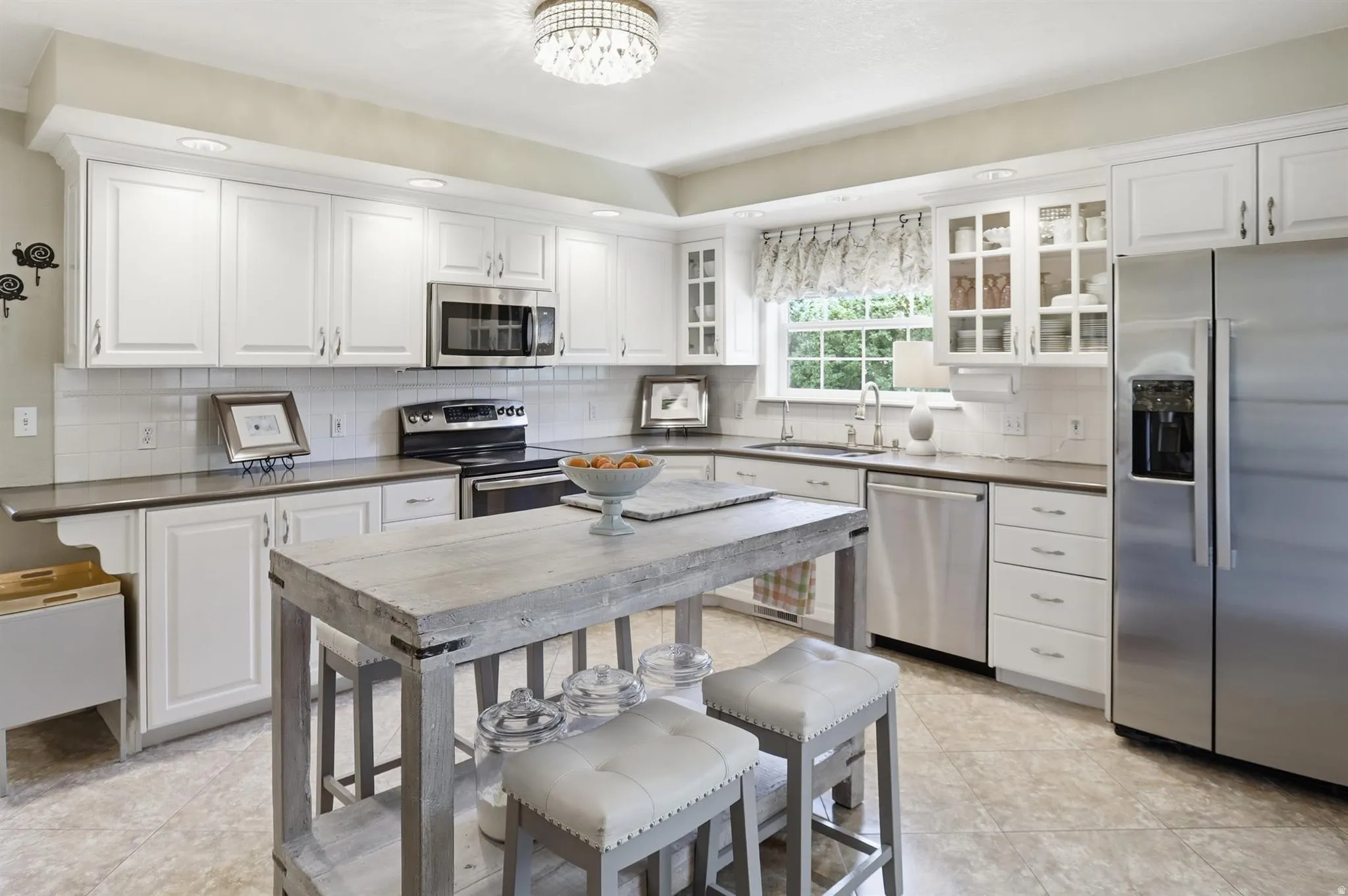 Kitchen featuring an island with seating, white shaker-style cabinetry, and stainless steel appliances