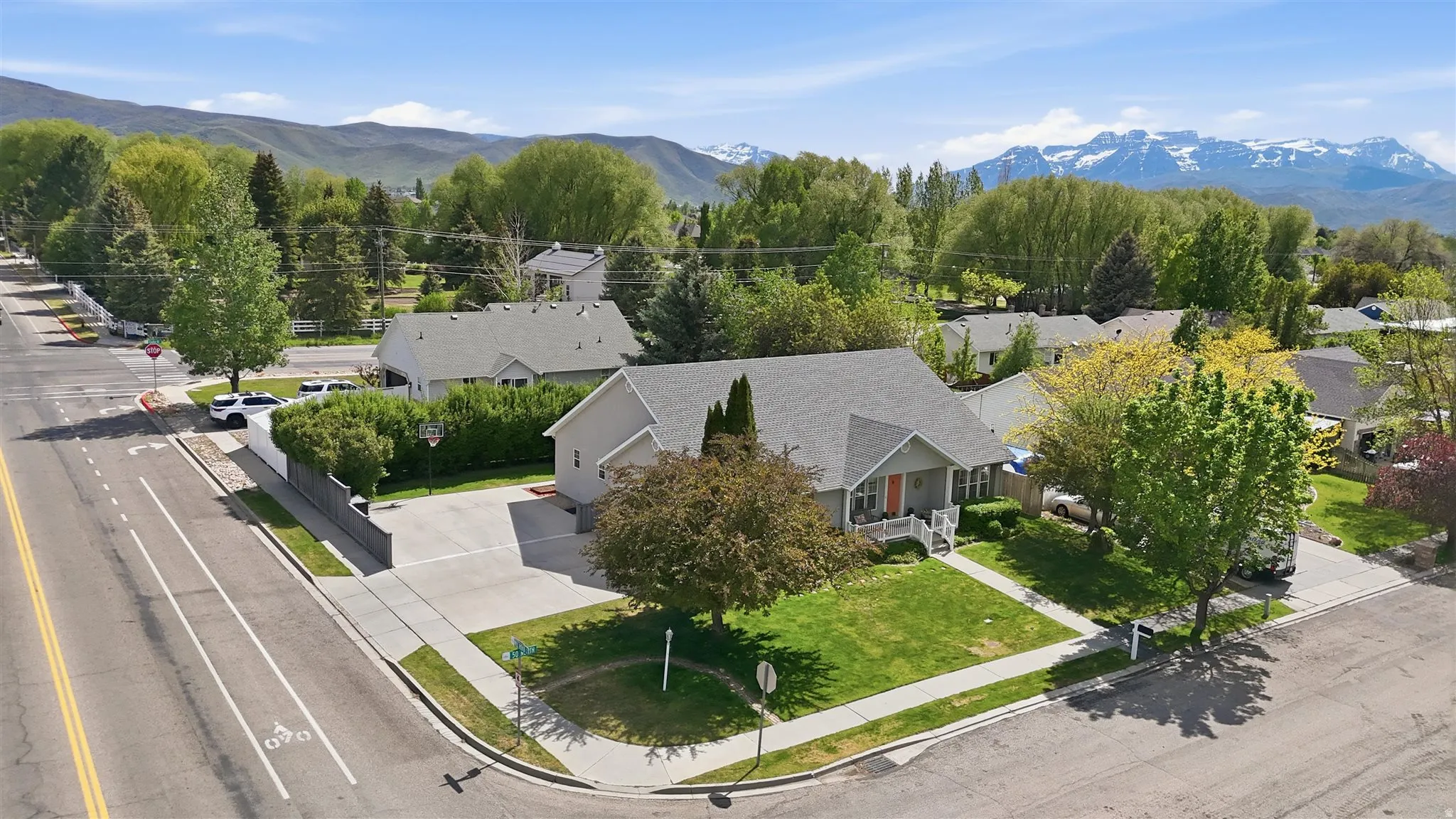 Corner lot property featuring mature landscaping and a paved driveway