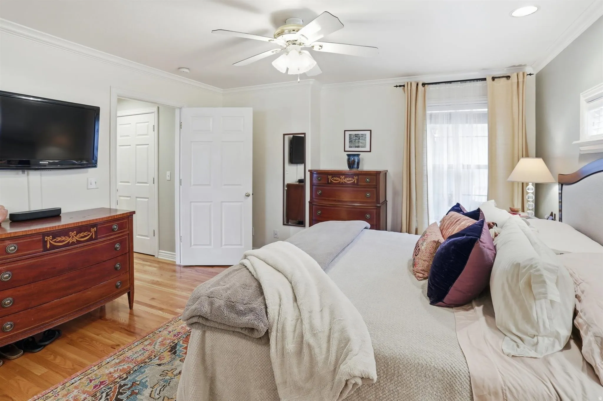 Hardwood flooring, crown molding, and recessed lighting enhance this bedroom
